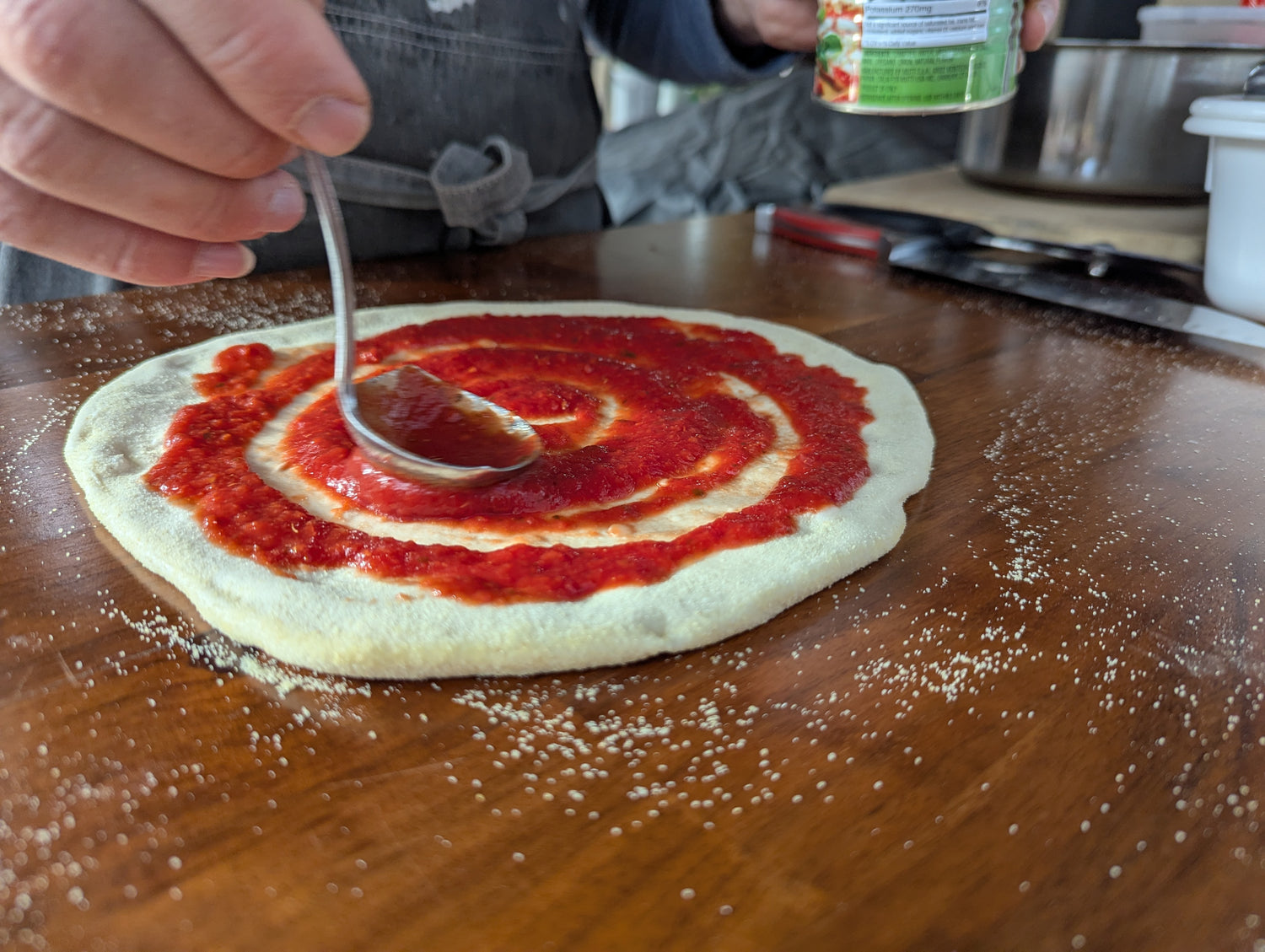 Guest spreading fresh sauce on pizza dough during Balloon Fiesta cooking class in Albuquerque