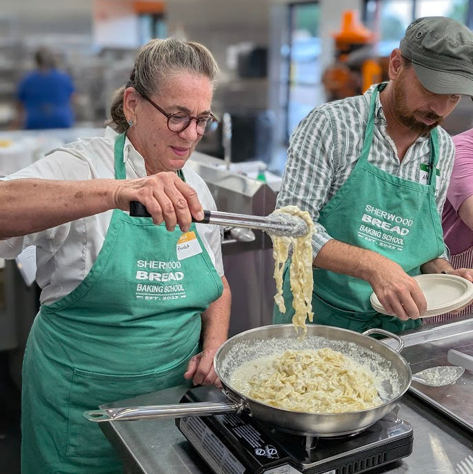 Participants making fresh pasta during a group cooking workshop in Albuquerque