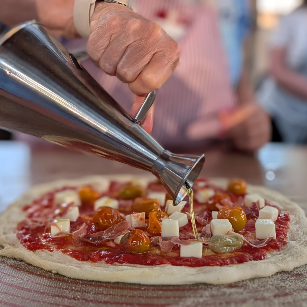 Olive oil being drizzled on homemade pizza during a sunset cooking class in Albuquerque