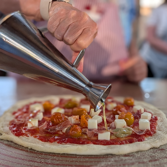 Olive oil being drizzled on homemade pizza during a sunset cooking class in Albuquerque