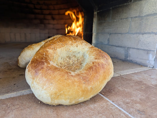 Freshly baked Uzbek flatbread (Lepeshka) straight from the wood-fired oven at a hands-on flatbread class in Albuquerque, part of Sherwood Coffee 'n' Bread’s cooking school experience.
