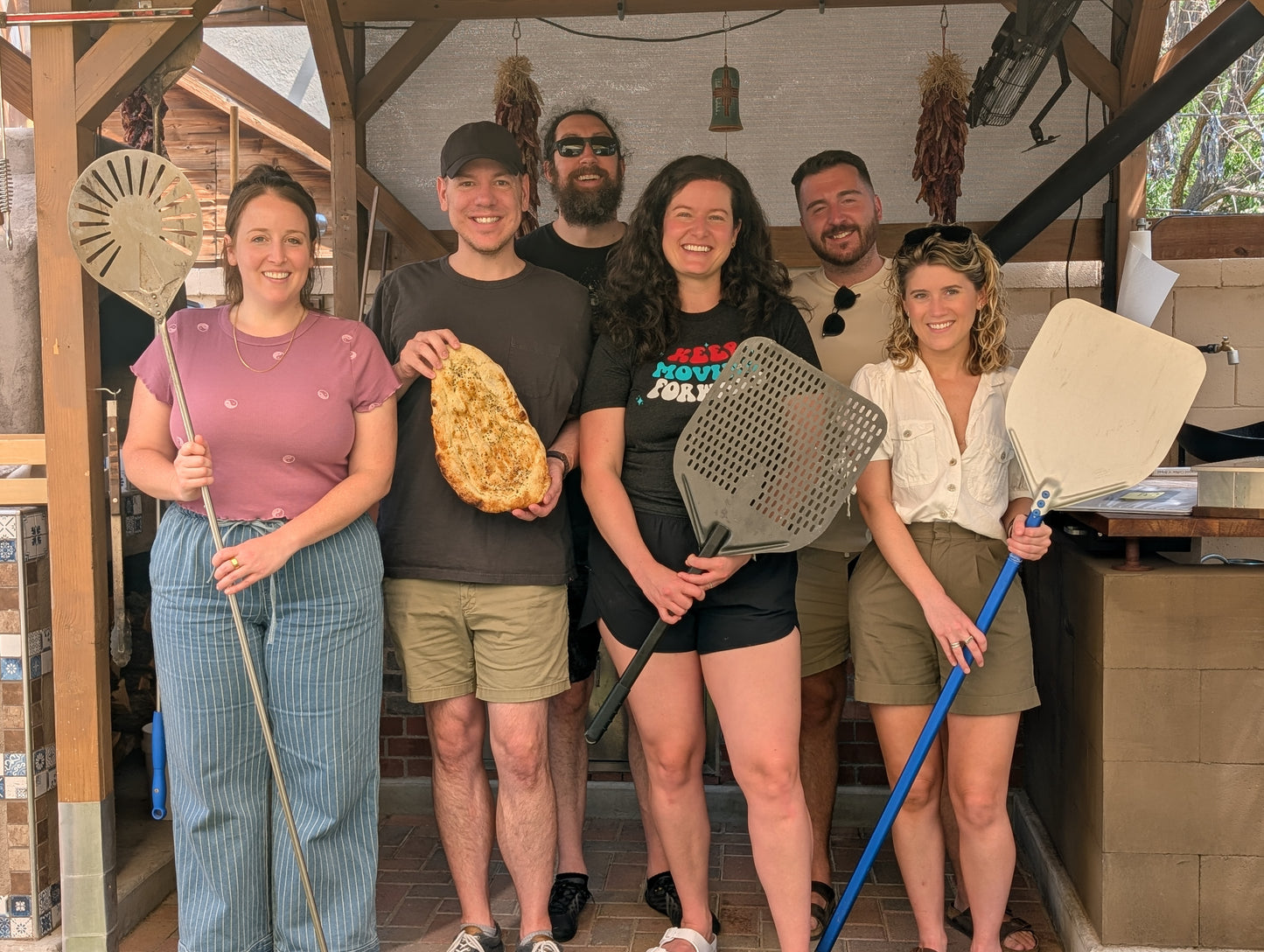 Team Building Activities in Albuquerque participants posing with pizza and bread during hands-on experiences.