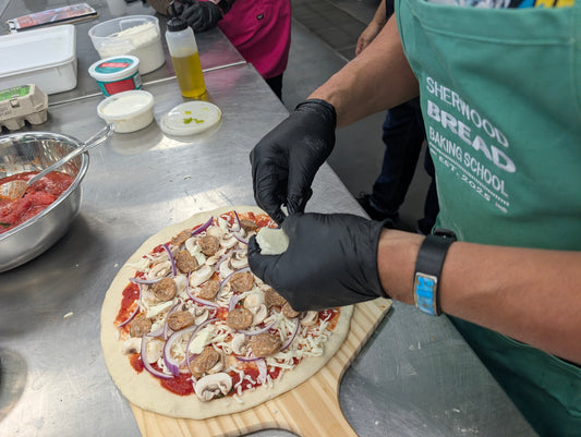 Student shaping fresh pizza dough at Sherwood Bread
