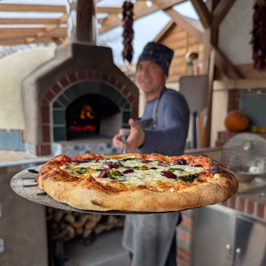 Igor Dernov holding a freshly baked pizza during Balloon Fiesta Week cooking class in Albuquerque
