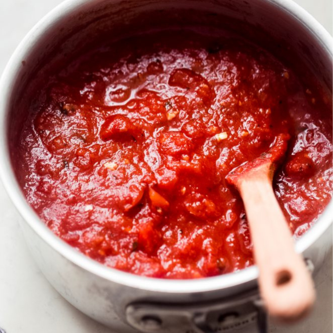 Fresh pizza sauce being spread during hands-on pizza class in Albuquerque