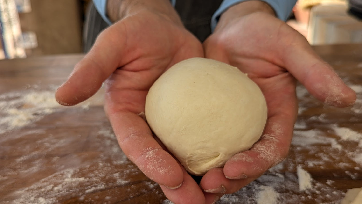 Hands shaping fresh pizza dough balls for wood-fired pizza